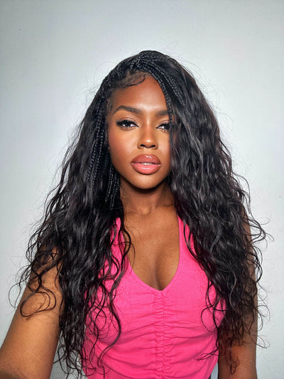 Woman with long, wavy hair wearing a pink top against a plain background